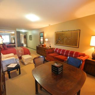 A cozy living room featuring a red sofa, wooden furniture, and warm lighting.