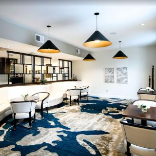 A modern restaurant interior featuring stylish lighting, contemporary furniture, and an abstract carpet design.