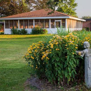 A charming house surrounded by vibrant flowers and well-kept grass, basking in the warm sunlight.