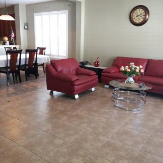 A stylish living room featuring red sofas, a glass coffee table, and an adjacent dining area.