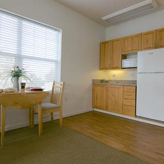 A cozy kitchen and dining area with wooden cabinets and a small dining table by the window.