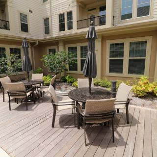 An inviting outdoor patio area featuring tables and chairs with umbrellas in an apartment courtyard.