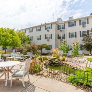 A sunny courtyard with patio furniture, landscaping, and a multi-story building in the background.
