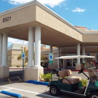 A golf cart parked in front of a building entrance with columns, under a clear blue sky.