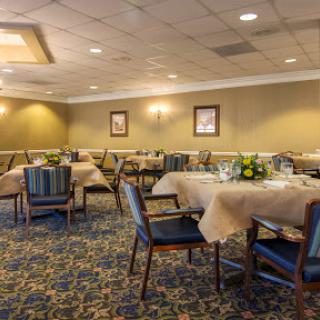 A spacious and elegantly arranged dining room, featuring neatly set tables and comfortable seating.