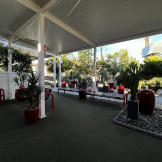 A shaded outdoor patio featuring chairs and potted plants under a covered roof.