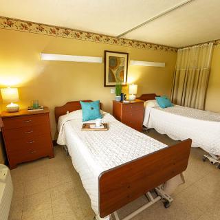 A cozy hospital room with two patient beds and warm lighting.
