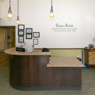 A reception area with a curved wooden desk, framed wall art, and pendant lighting.