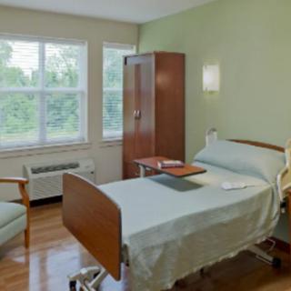 A clean and well-lit hospital room with a single bed and a window view.