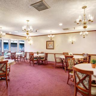 A cozy and elegantly furnished dining room featuring tables, chairs, and attractive lighting.