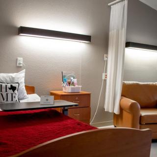 A modern hospital room with a bed, side table, curtain divider, and couch.