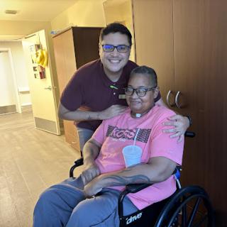 A caring moment between a caregiver and an elderly individual, both smiling for the photo.
