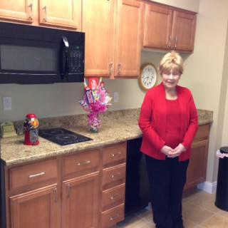 A woman standing in a kitchen with wooden cabinets and modern appliances.