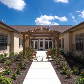 A beautifully landscaped entrance pathway leading to a building under a clear blue sky.
