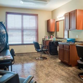 A tidy and well-lit hair salon with styling stations and chairs.