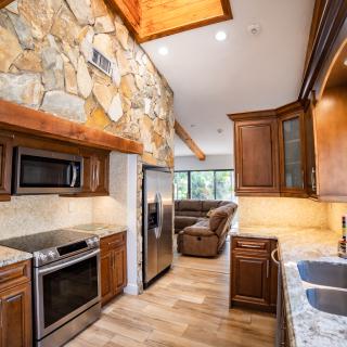 A modern kitchen with wooden cabinets, stone wall accents, and stainless steel appliances.