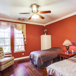 A cozy bedroom with twin beds, red walls, and natural light from a large window.