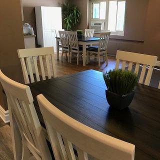 A dining area with a dark wooden table, surrounded by white chairs, and a small plant centerpiece.