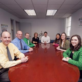A group of individuals seated around a conference table in an office setting.