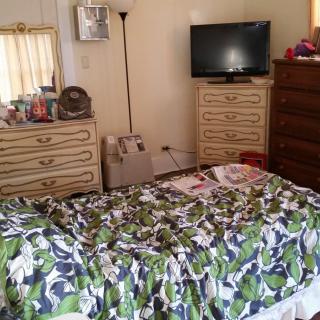 A cozy bedroom with a colorful bedspread, TV, and dresser.