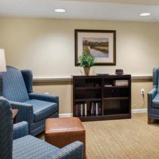 A cozy living room with blue armchairs, a bookshelf, and wall art.