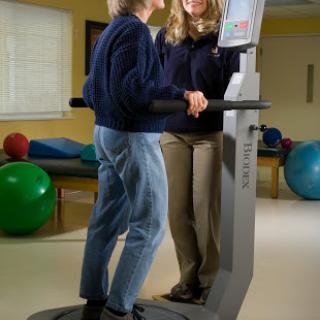 A therapist assists a patient during a rehabilitation exercise using specialized equipment.