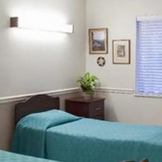 A simple and clean bedroom with two twin beds, a bedside table, and minimal decorations.