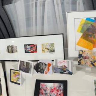 A collection of framed artworks and collages displayed on a table, featuring a variety of colorful designs.