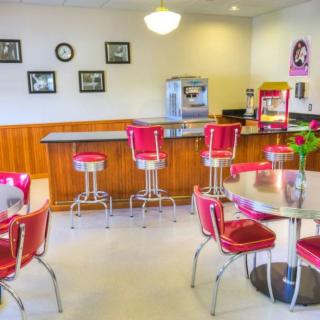 A retro-style diner interior featuring red bar stools and chairs, with vintage decor.