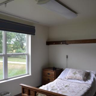 A simple bedroom with a single bed next to a window.