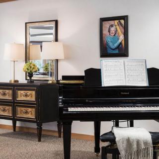 A cozy living room featuring a grand piano, decorated with elegant furniture and artwork.