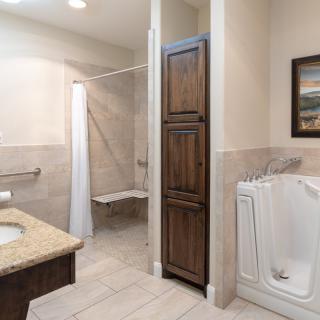 A modern bathroom featuring a walk-in tub and accessible shower with beige tile flooring.