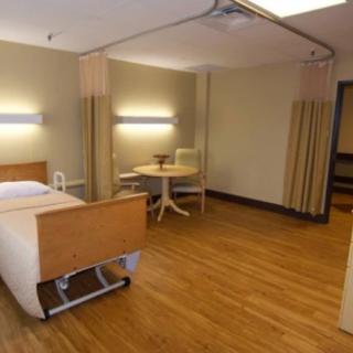 Modern hospital room with a patient bed and seating area.
