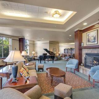 A spacious lounge with comfortable seating, featuring a grand piano and a cozy fireplace.