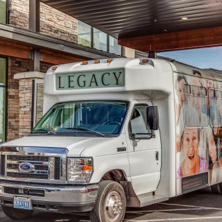 A white bus labeled 'Legacy' parked outside a building.
