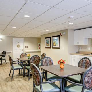 A well-lit dining area with tables and chairs, complemented by a small kitchenette.