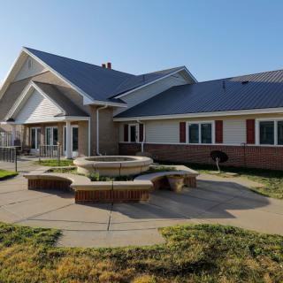 A single-story residential building with a fountain in the front yard.