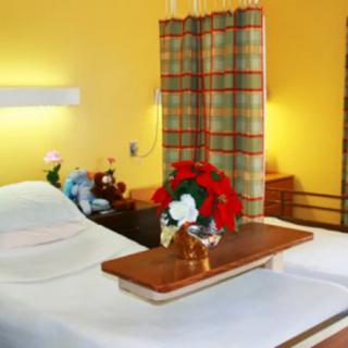 A hospital room with a bed, floral arrangement, and a privacy curtain.