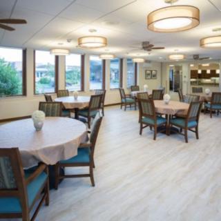 A spacious and well-lit dining area with multiple tables and chairs, featuring large windows and modern lighting fixtures.