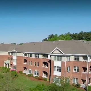A three-story brick apartment building in a suburban setting during the day.