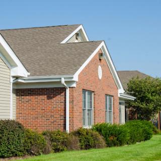 A charming residential house featuring a brick facade and well-manicured landscaping.