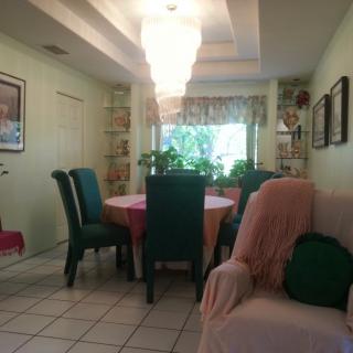 A cozy dining room with a round table, green chairs, and a chandelier above.