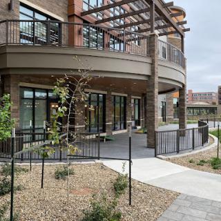A modern residential building featuring outdoor seating and landscaped pathways.