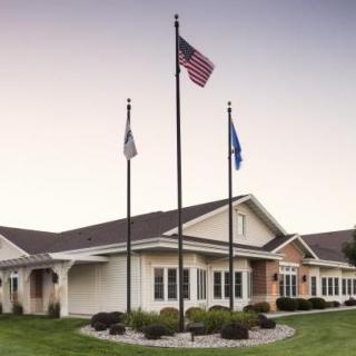 A building with three flags flying in front of it, under a clear sky.