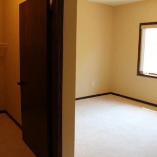 An empty room with a window and carpet, viewed through a doorway.
