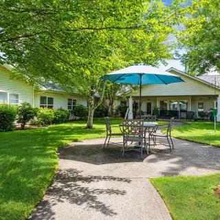 A sunny backyard patio with a table and umbrella set amidst a lush garden.