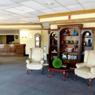 A cozy hotel lobby with armchairs and a decorative bookshelf.
