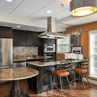 A modern kitchen featuring stainless steel appliances, a central island with bar stools, and warm-toned decor.