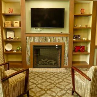 A cozy living room setup featuring a fireplace, television, and decorative shelves.