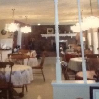 A cozy restaurant interior with tables and chairs arranged neatly under elegant chandeliers.